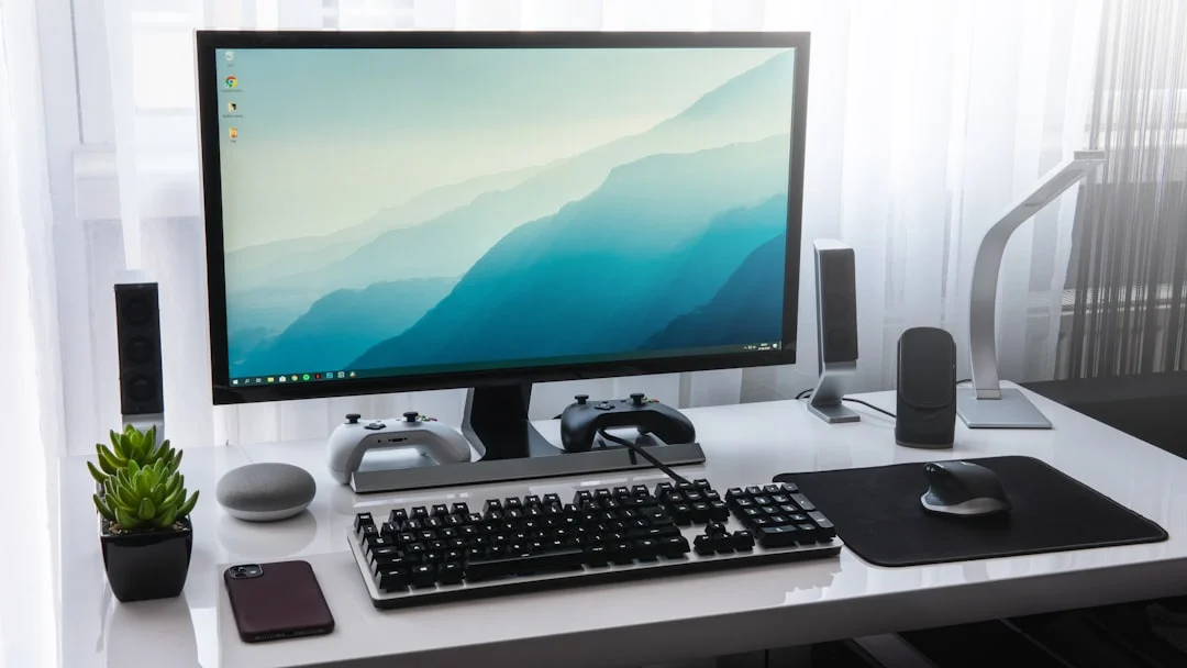 A clean desk setup featuring a large ultrawide monitor displaying a 3D render, a custom water-cooled gaming PC with RGB lighting, and a mechanical keyboard, photographed in warm ambient light